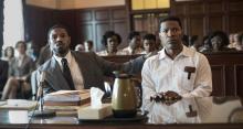 Michael B. Jordan, as attorney Bryan Stevenson, and Jamie Foxx, as defendant Walter McMillian, sit at a table in a courtroom.