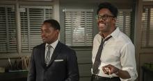 Aml Ameen and Colman Domingo stand smiling in a meeting room.
